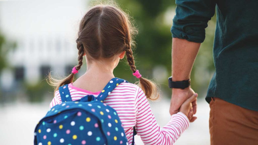 Una bambina accompagnata a scuola dal papà.
