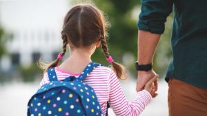 Una bambina accompagnata a scuola dal papà.